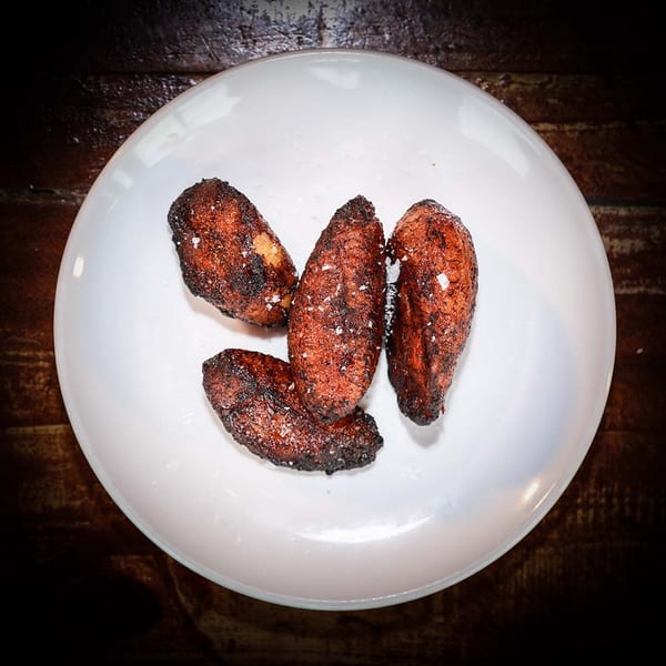 Four golden-brown fried plantains, sprinkled with sea salt, on a white plate.