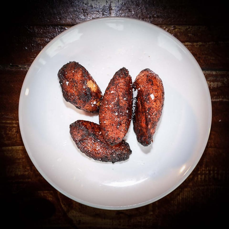 Four golden-brown fried plantains, sprinkled with sea salt, on a white plate.