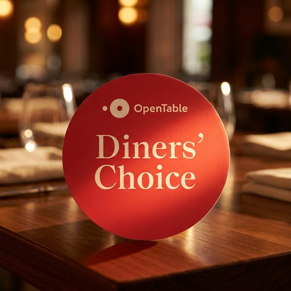 OpenTable Diners' Choice award on a restaurant table with place settings and blurred background.