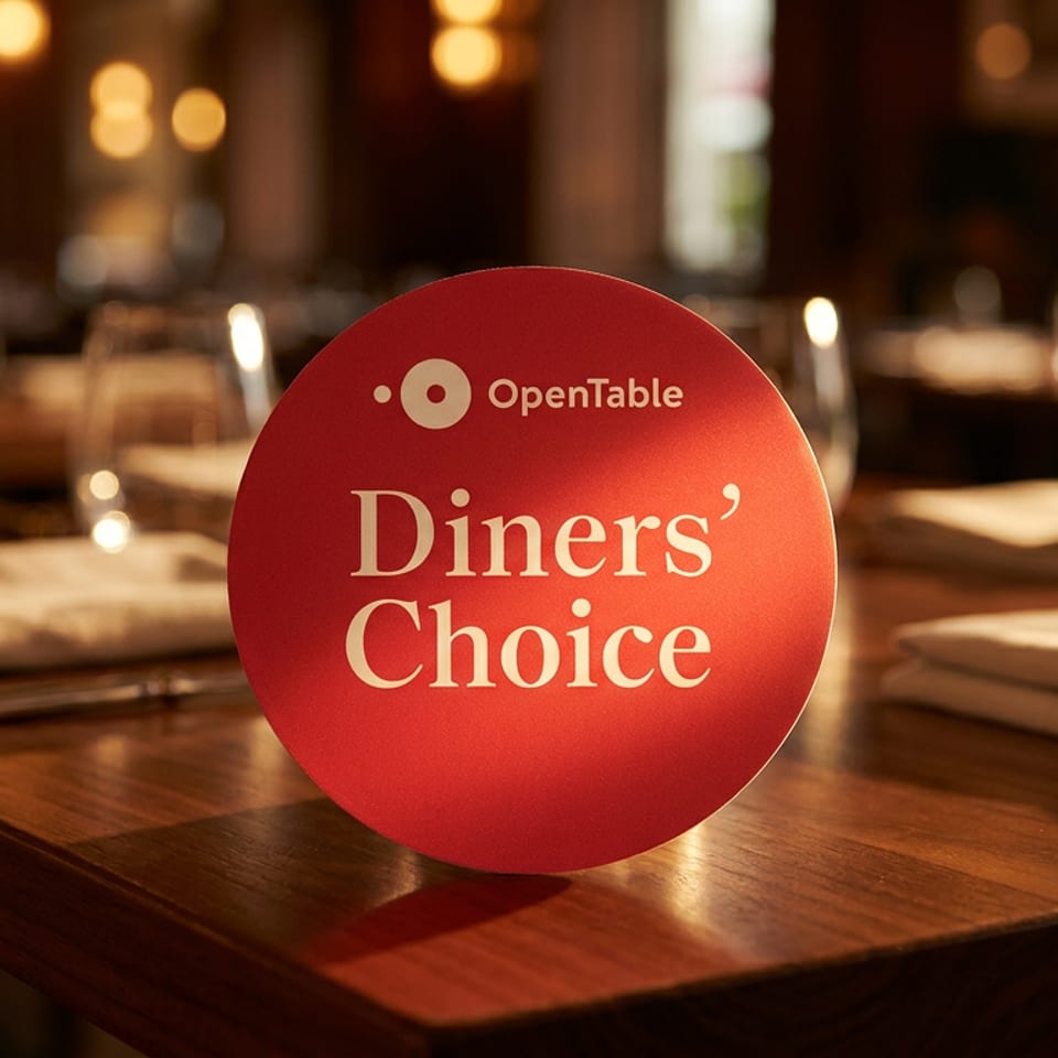 OpenTable Diners' Choice award on a restaurant table with place settings and blurred background.