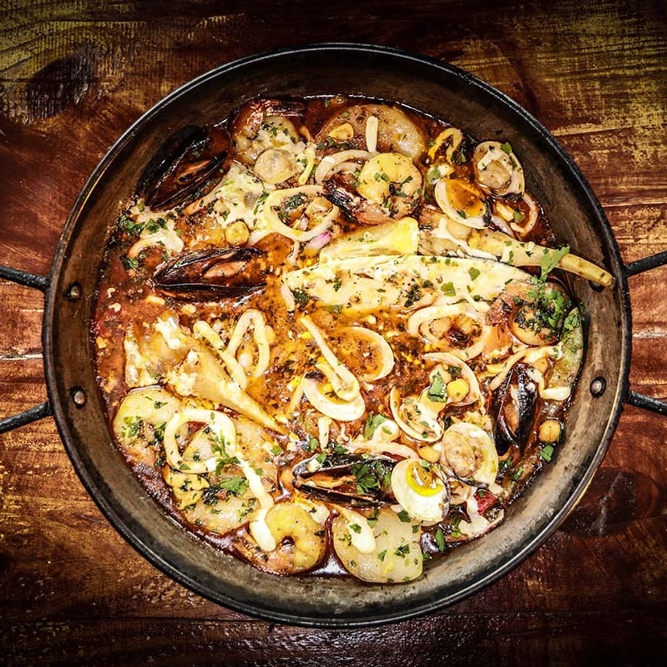 Overhead view of a paella pan filled with seafood, including mussels, shrimp, and squid.